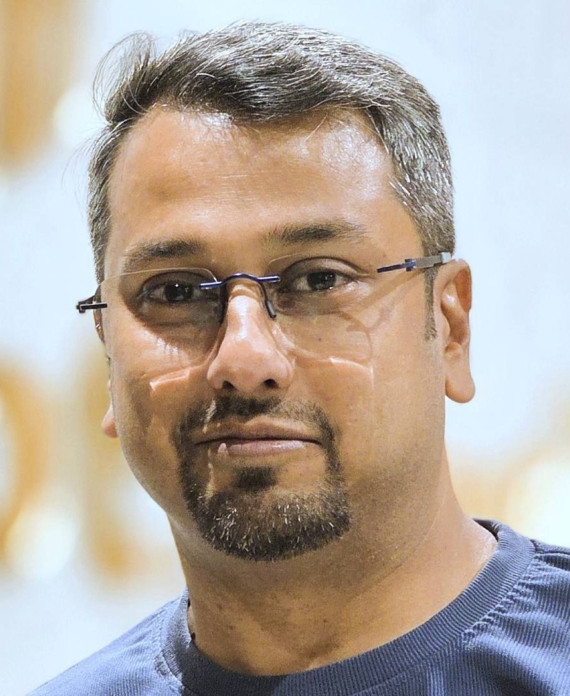 Rahul Mullick Professional portrait of a business leader wearing glasses and a blue shirt, taken in a corporate environment.